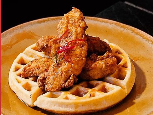 Crispy chicken on a Belgian waffle, hot honey poured over