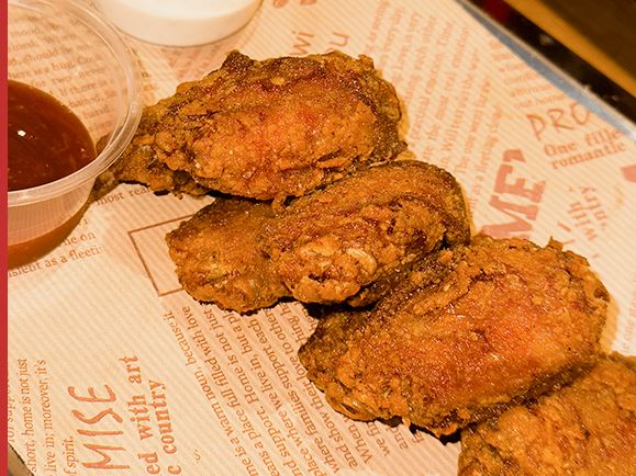 Fried chicken wings on newsprint with a dip
