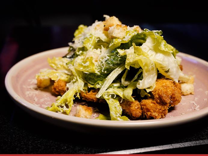 A caesar salad with crispy chicken and croutons