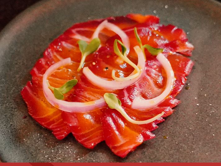 Thinly sliced cured salmon with shaved onion