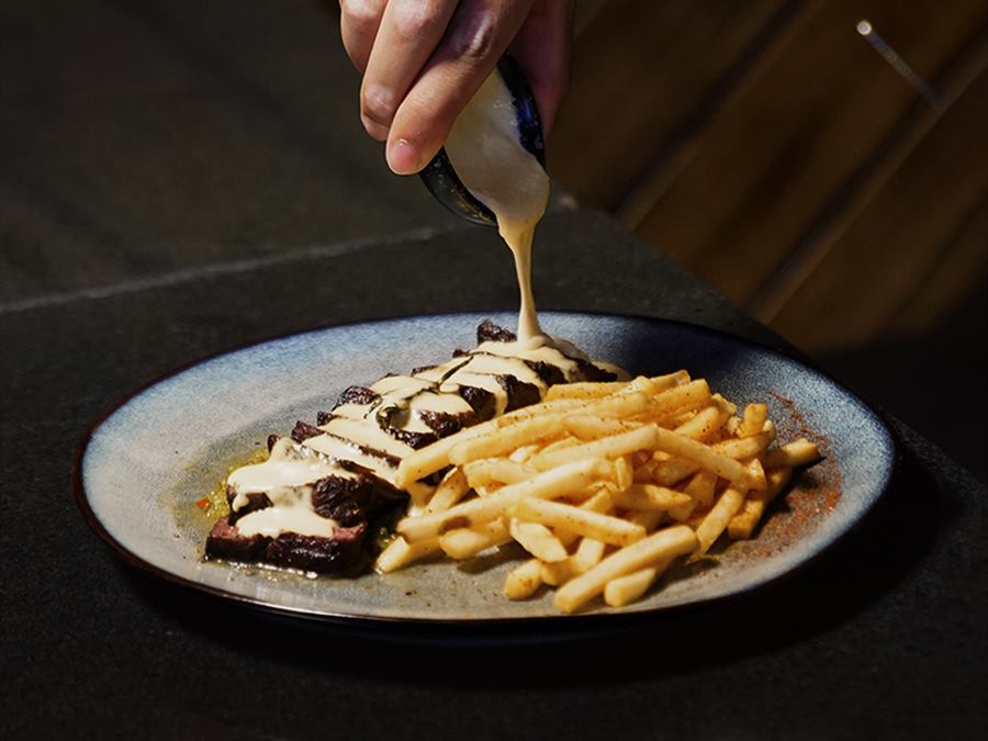Sliced steak and frites, sauce poured over
