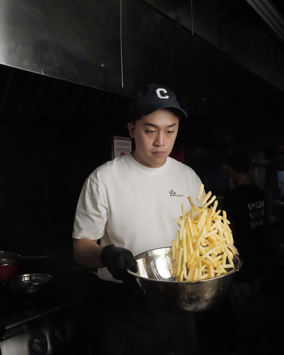 A cook holding a steel bowl of frites