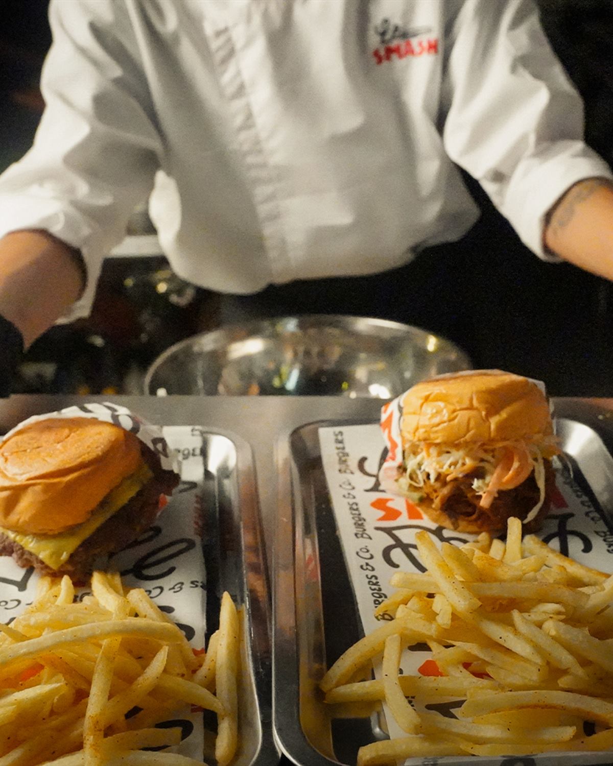 Burgers and fries lined up on trays at the pass