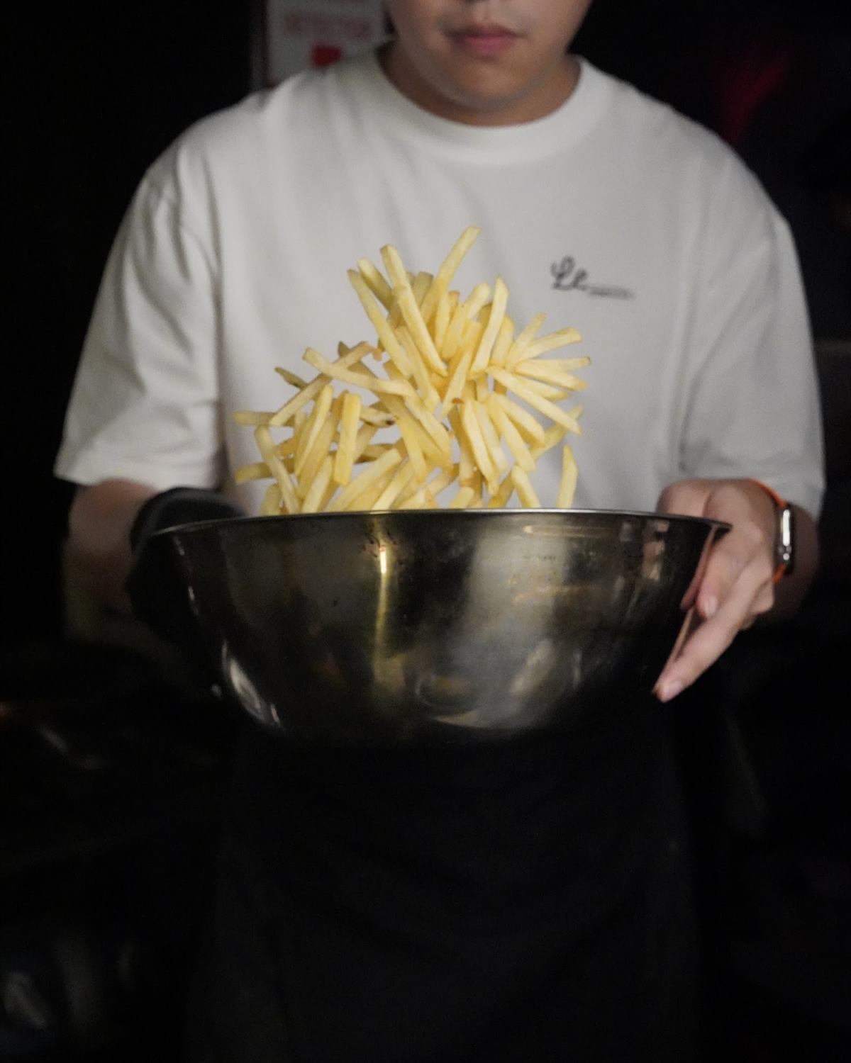 A cook holding out a bowl heaped with frites