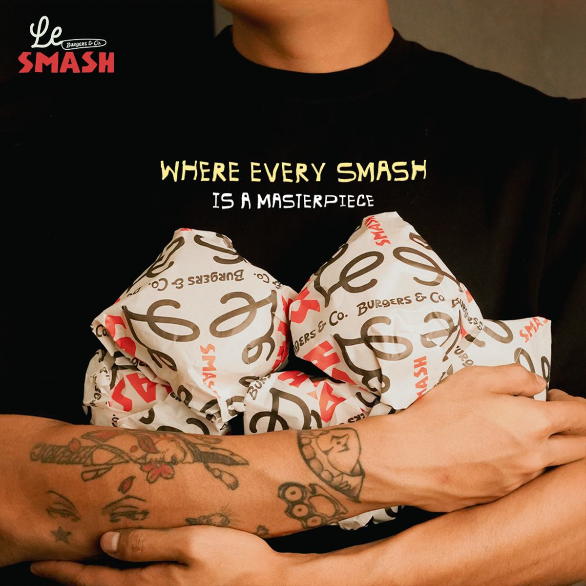Where every smash is a masterpiece — four wrapped burgers held in tattooed arms