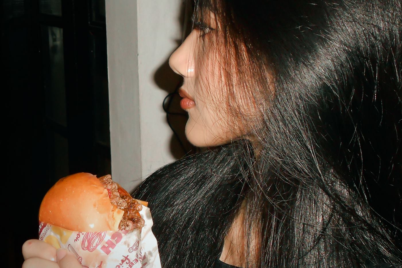 A guest holding a wrapped burger, seen in profile