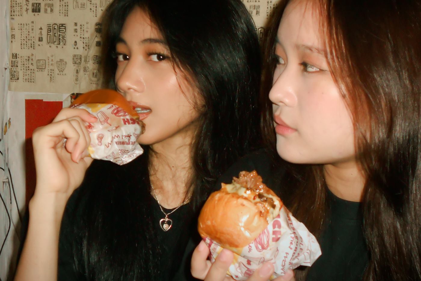 Two guests eating wrapped burgers side by side