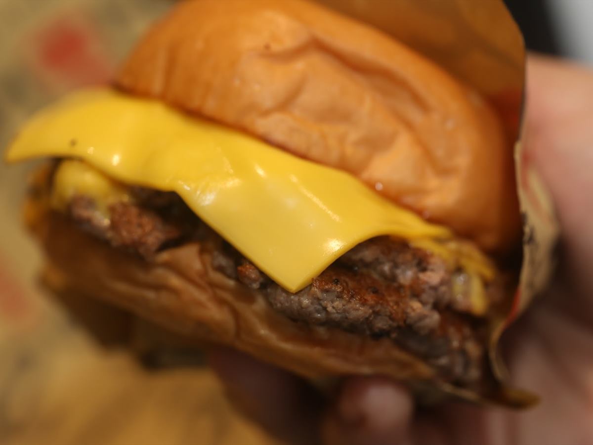 A cheeseburger held close, the cheese draped over the patty