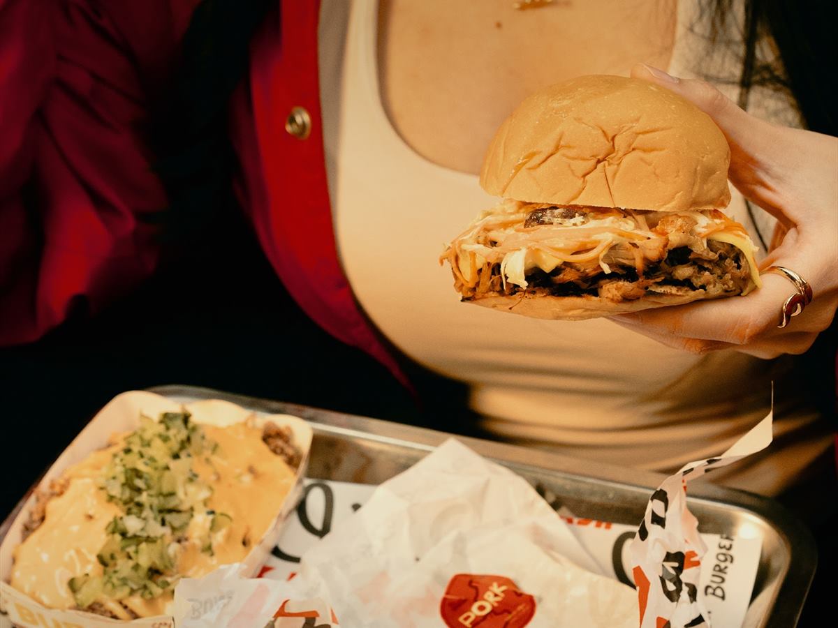 A burger held over a loaded tray