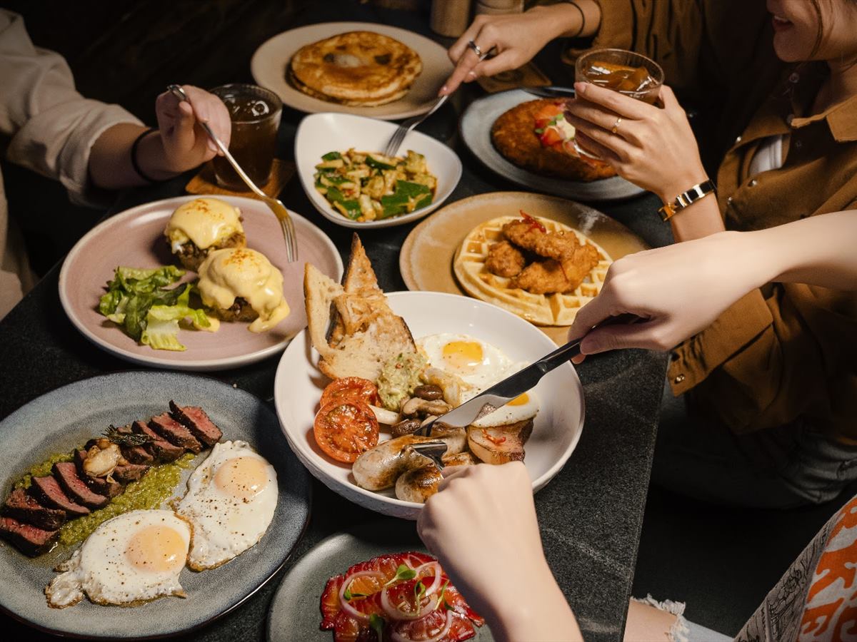 The brunch table photographed from above, hands reaching in