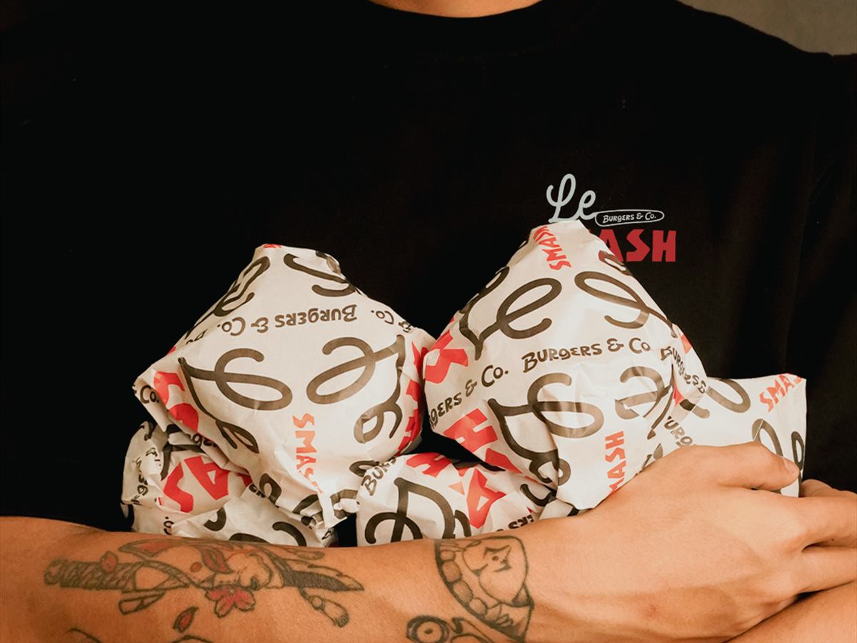 Four wrapped burgers held in two arms