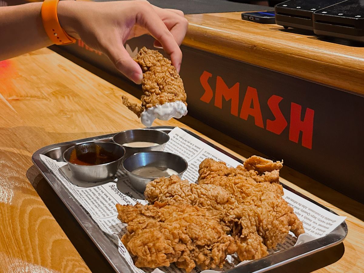 A hand lifting a tender off the tray at the counter