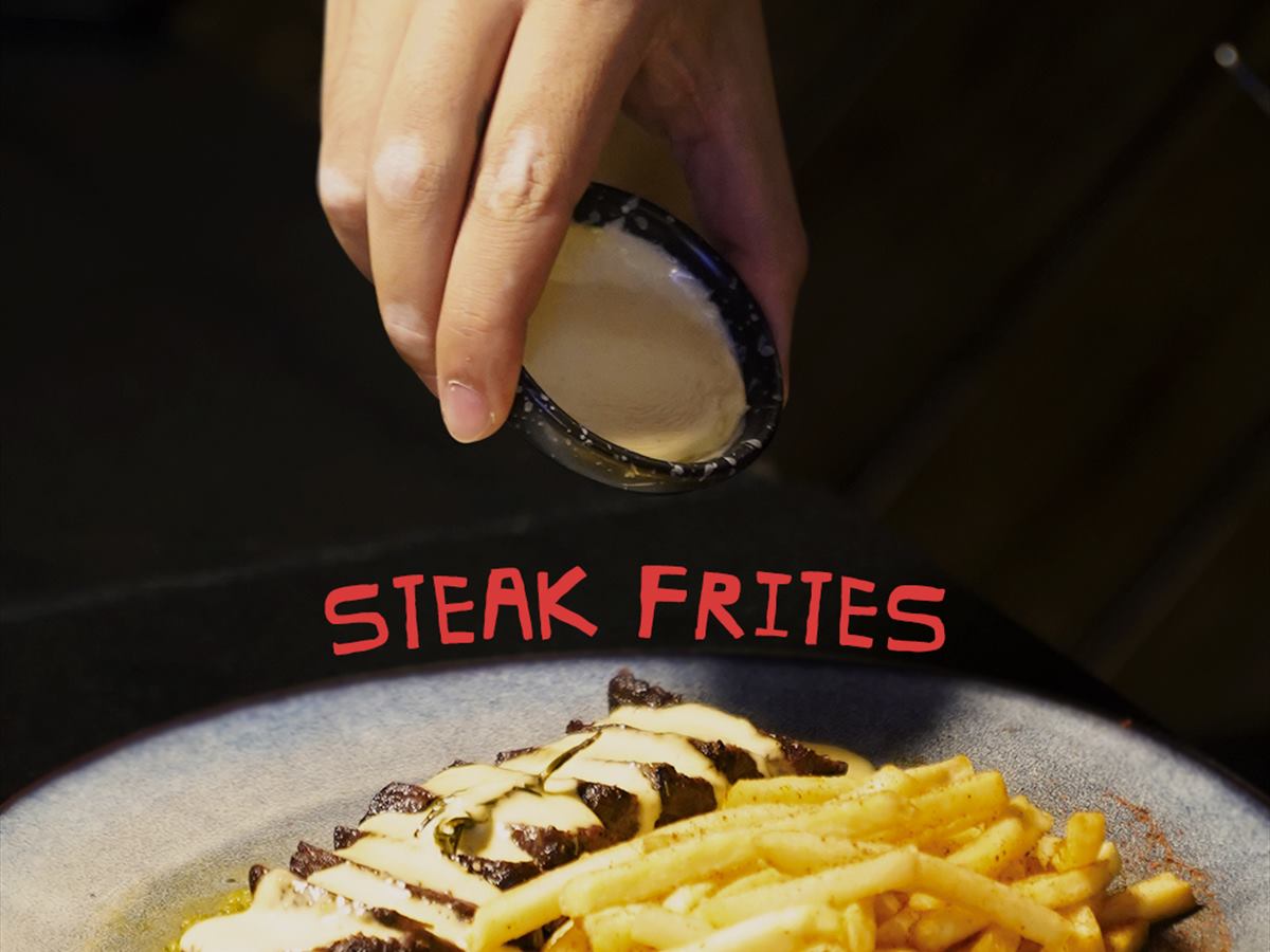 Steak frites, sauce being poured over